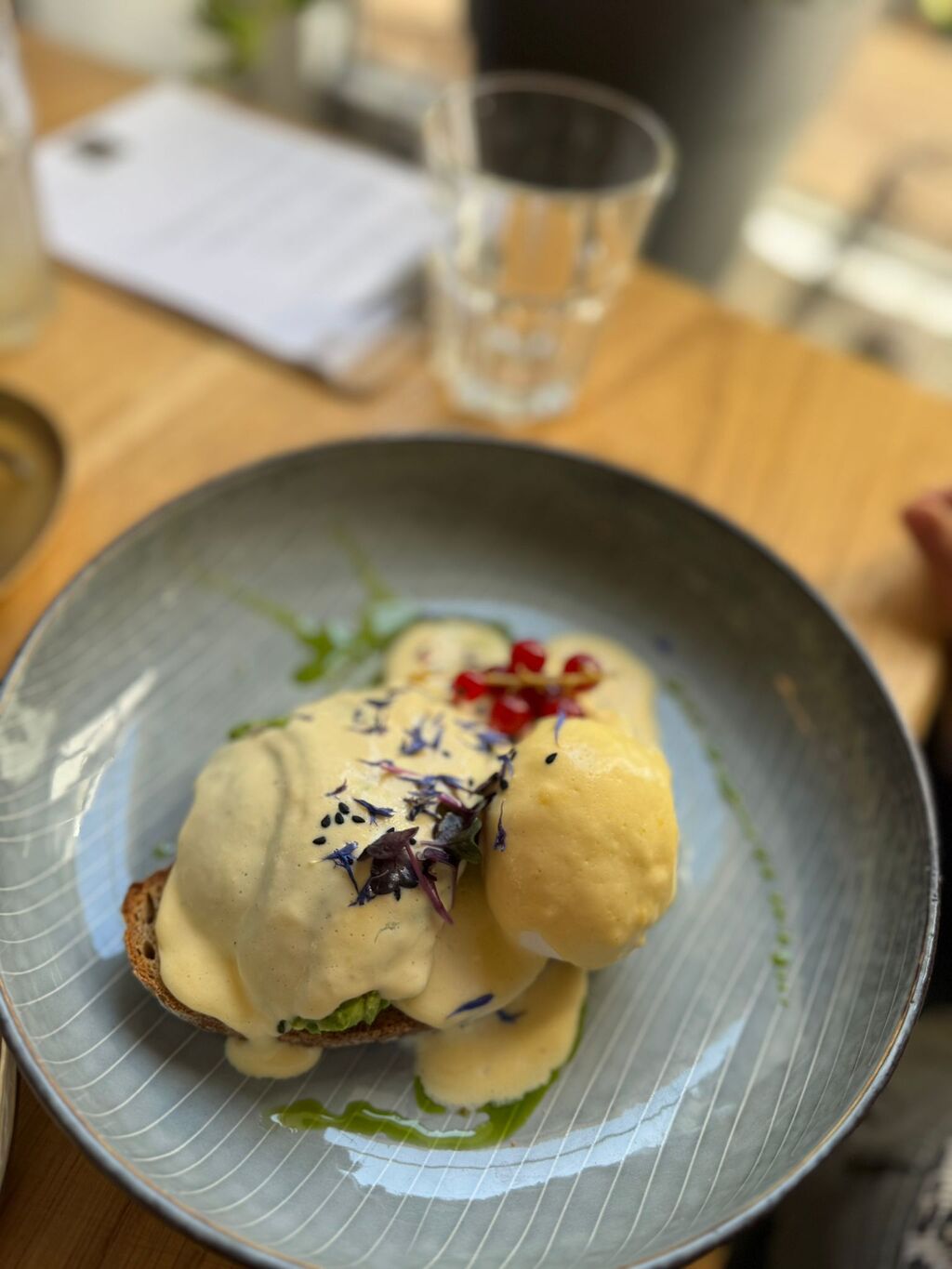 Ein Teller mit Brot belegt mit Avocado, pochiertem Ei und cremiger gelber Sauce
