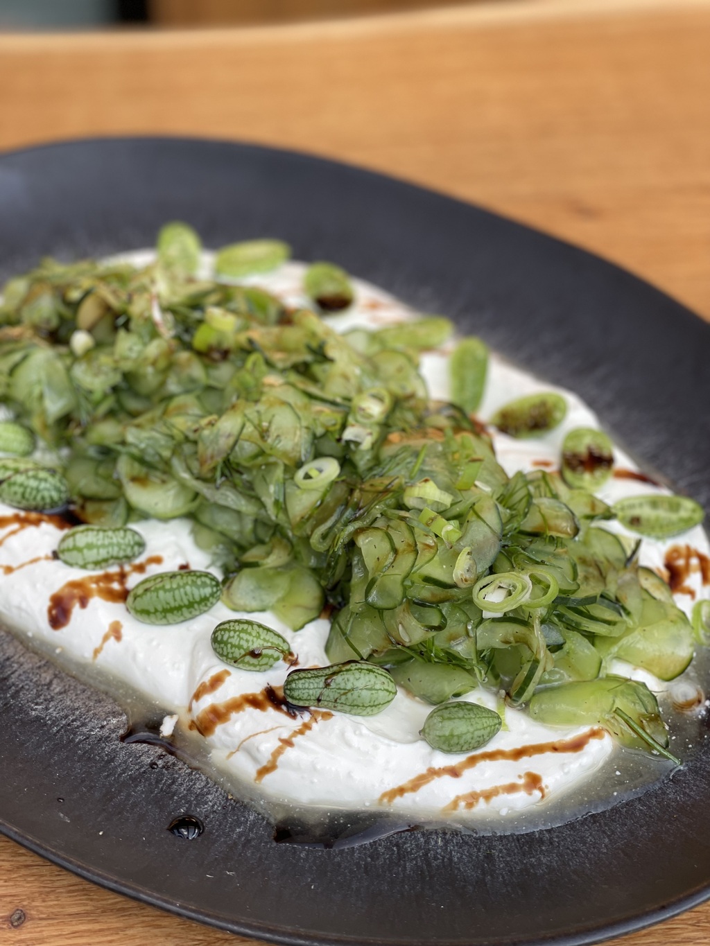 Ein Teller mit cremigem Joghurt und grünem knackigem Gemüse dekorativ angerichtet