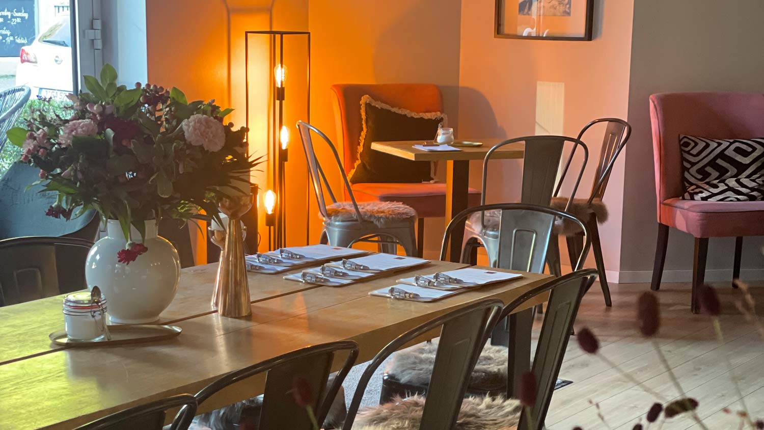 Gemütliches Café mit rosafarbenen Stühlen, Holztisch und warmer Beleuchtung
